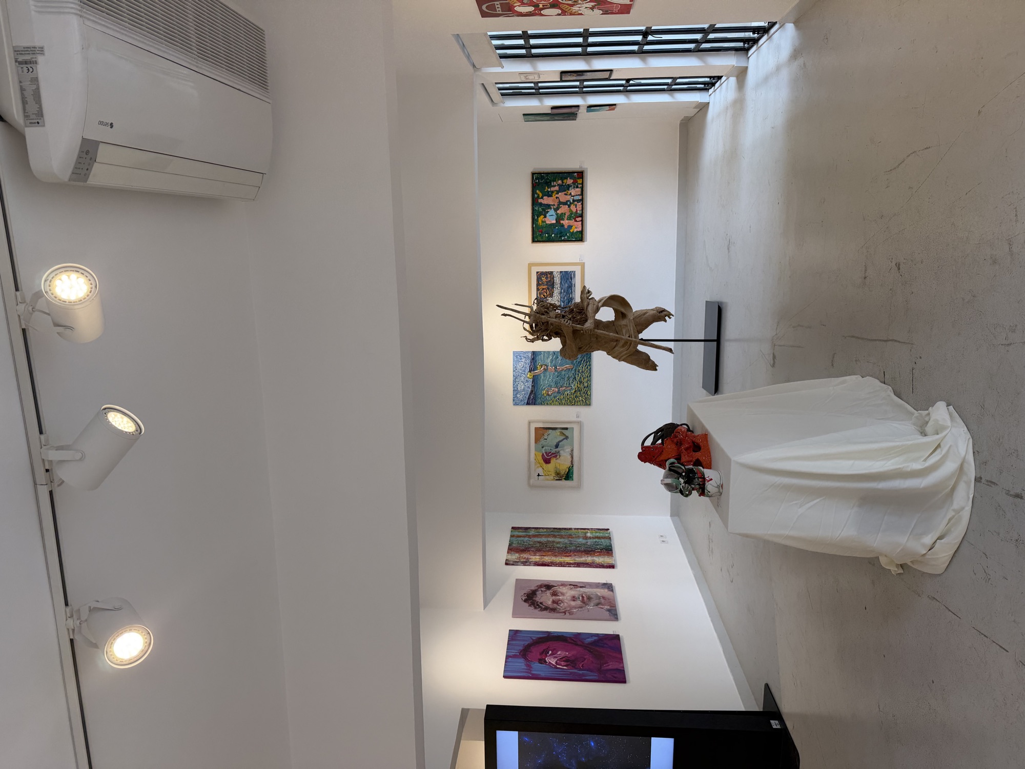 The main room of The Holly Art Gallery: paintings on white walls, a sculpture and a plinth.